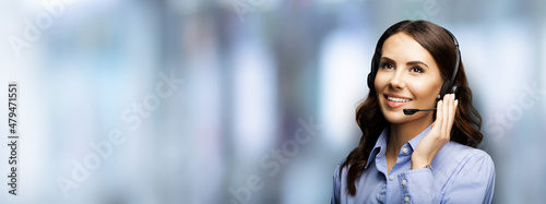 Call center help line service. Portrait of customer support phone sales operator in headset, over blurred modern office interior background. Young brunette business woman, indoors. photo