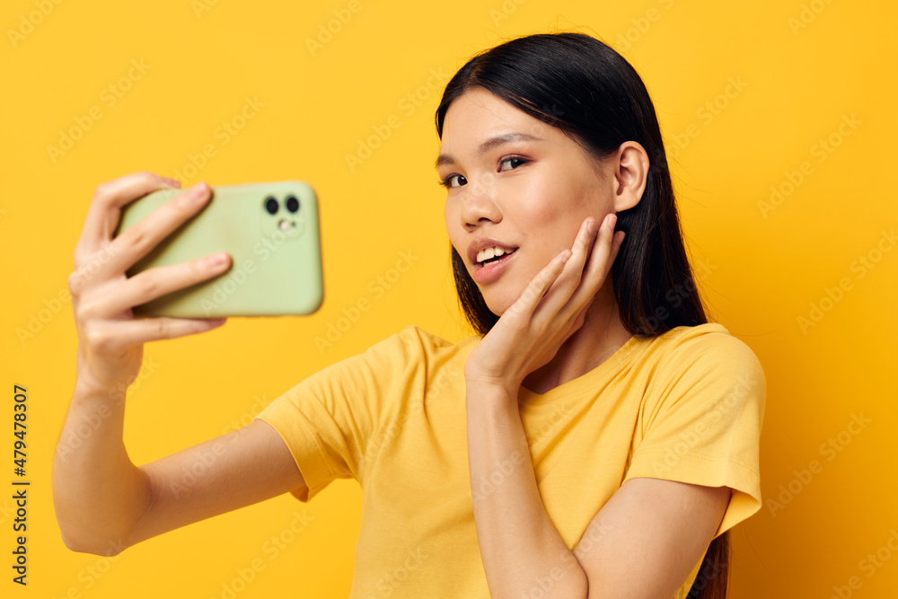 Charming young Asian woman in a yellow t-shirt looking at the phone posing Lifestyle unaltered Charming young Asian woman in a yellow t-shirt looking at the phone posing Lifestyle unaltered