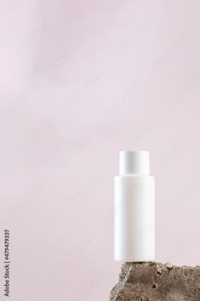White empty bottle of cosmetics on a concrete podium on a pink background close-up. Copy space. White empty bottle of cosmetics on a concrete podium on a pink background close-up. Copy space.