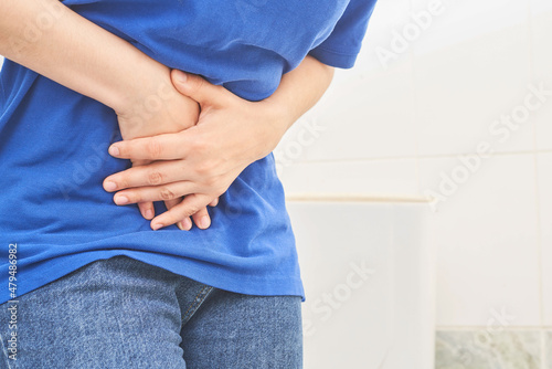 Woman is holding her belly, concept of stomach ache, menstrual cramps, indigestion, gastrointestinal and diarrhea problem