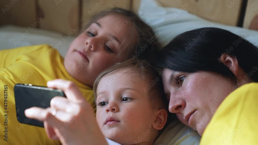 Happy family concept. Mom, daughter and son are play on bed. Child