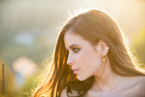 Beautiful young woman, tender girl looking eways in summer park. Fashion and beauty. Young woman on sunny summer day side profile portrait. photo