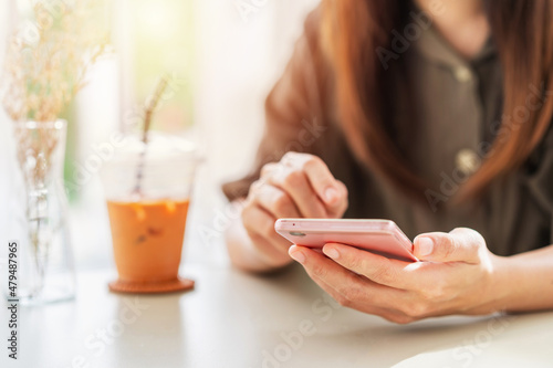 Young woman with drinks using mobile phone and relaxing in cafe  Modern lifestyle