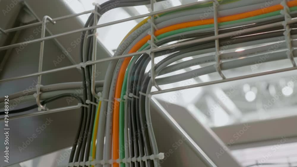 In industrial production many wires of different colors are laid in a metal tray and diverge to their equipment. Shot in motion. Closeup