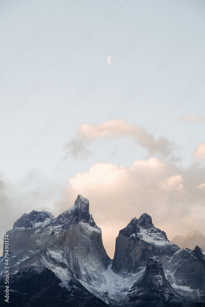 Part of the Torres del Paine mountains (peaks) against the cloudy sky Snow-capped peaks of mountains in an unusual shape against the sky with clouds and in the distance a small month. dust