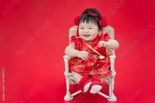 Chinese Infant baby girl smiling and laughing as concept of Chinese New Year. Happy Cute Asian infant baby sitting, smiling and laughing on red background. © molpix