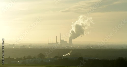 Time-lapse of a powerplant as it pushes out steam with clouds moving behind it in a hazy smoggy atmosphere. photo