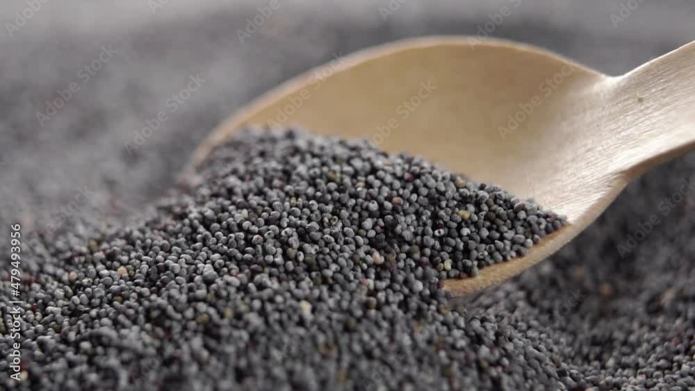 Dry poppy seeds. Spooning organic black grains into a wooden spoon in slow motion. Macro shot. Vegetable super food fiber Dry poppy seeds. Spooning organic black grains into a wooden spoon in slow motion. Macro shot. Vegetable super food fiber
