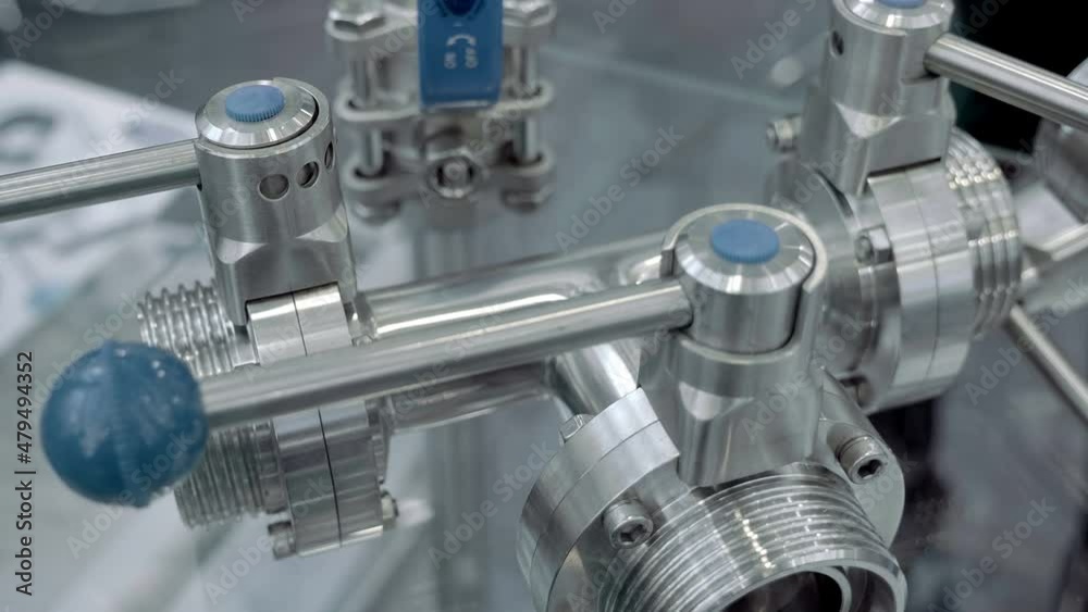 Modern stainless steel industrial ball valves with blue lever used in the food industry. Shot in motion. Closeup Modern stainless steel industrial ball valves with blue lever used in the food industry. Shot in motion. Closeup