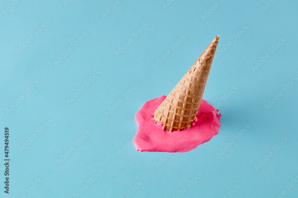 Dropped upside down ice cream cone with melting scoop on pastel blue