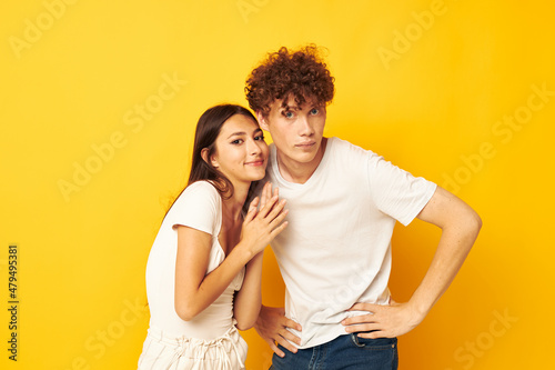 young boy and girl standing side by side in white t-shirts posing yellow background unaltered