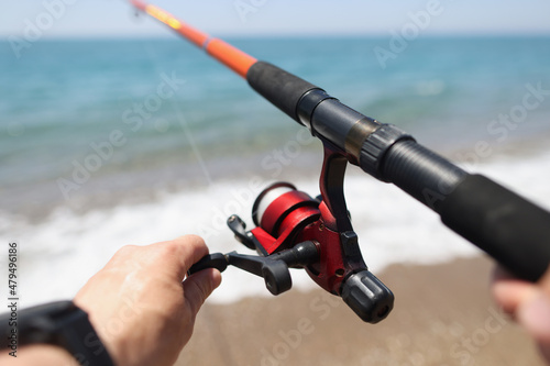 Hands hold a fishing rod against the background of sea coast