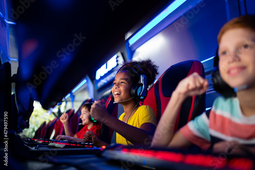 Group of cheerful excited children or professional gamers playing video games on computer in game room.