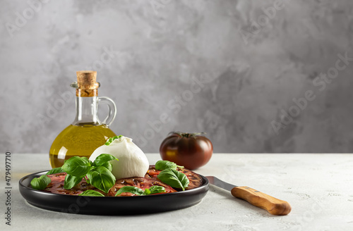 Buffalo burrata cheese served with fresh tomatoes and basil leaves. Delicious Italian appetizer. copy space.