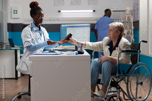 Physician doctor holding pills bottle explaining sickness diagnosis to senior invalid woman discussing medication treatment during medical appointment in hospital office. Concept of checkup visit