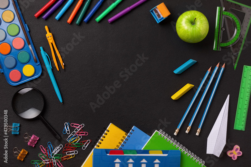 Frame made of school supplies and stationery on a blackboard background, the concept of learning in elementary school and high school, copy space for text photo