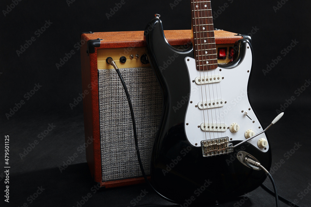 Naklejka premium Combo for guitar with black guitar on black background.