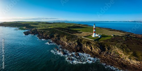an aerial view of tarbat ness lighthouse on easter ross in the highlands of scotland near inverness showing blue sky and calm seas with the lighthouse dominating the scene and rocks photo