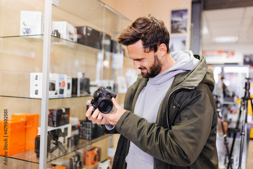 Young man examining camera in store Young man examining camera in store