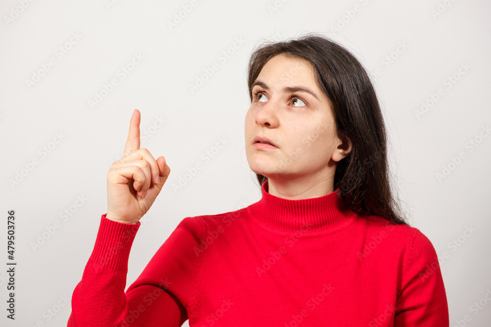 A brunette woman in red looks up and points her finger at a place for text A brunette woman in red looks up and points her finger at a place for text