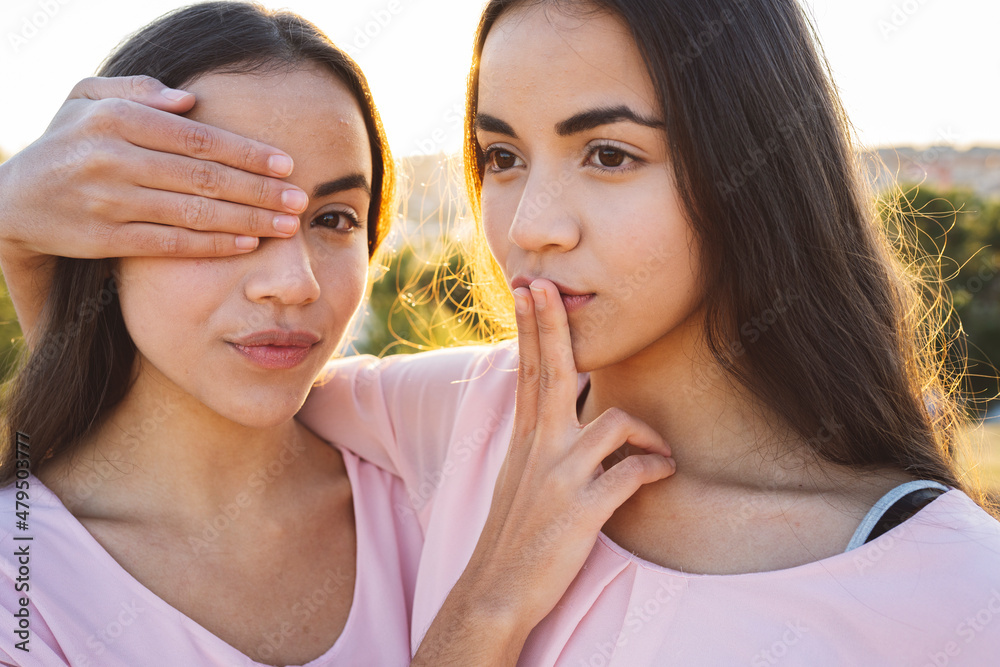 Sisters covering each other's eye and mouth Sisters covering each other's eye and mouth