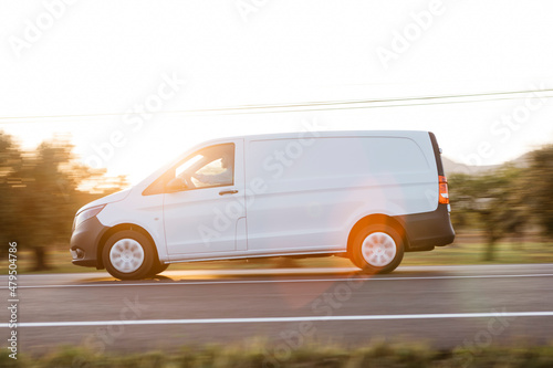 Delivery man driving van on road at sunset