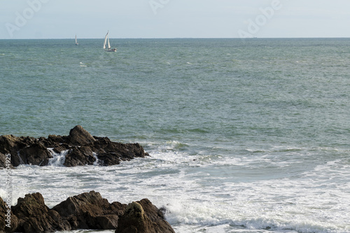 Bord de mer rocheux avec un voilier qui navigue 