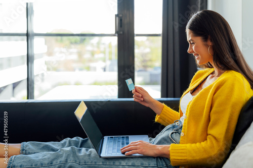 Happy woman with credit card doing online shopping in living room photo