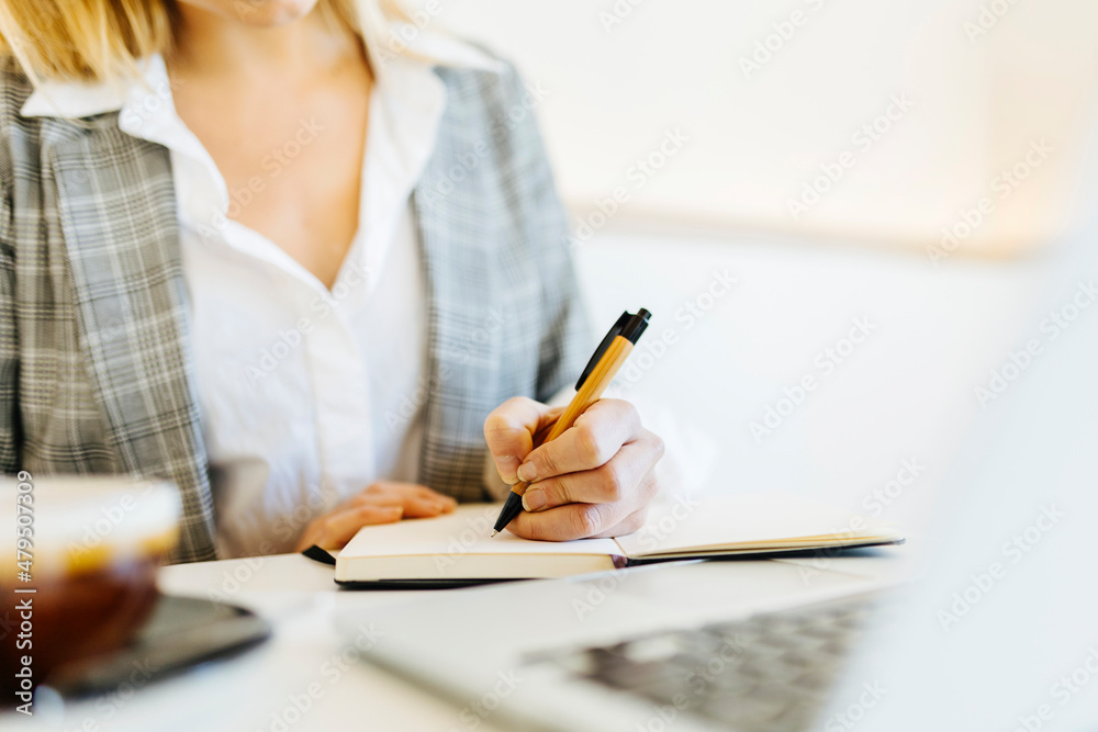 Young businesswoman writing in diary at cafe Young businesswoman writing in diary at cafe