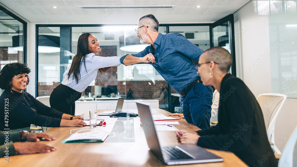 Modern businesspeople elbow bumping each other before a meeting Modern businesspeople elbow bumping each other before a meeting