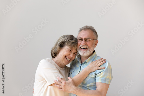 Sincere laughing bonding happy middle aged senior married couple cuddling, having fun enjoying communicating, isolated on white wall, showing candid loving feelings, good family relations concept.