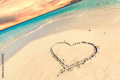 Heart on sand on tropical beach at sunset.