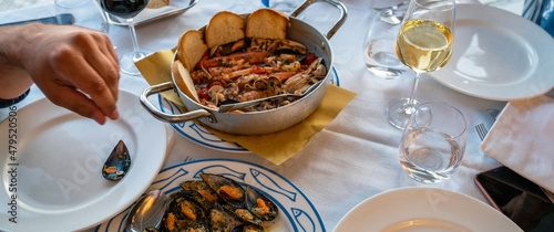 Mussels with herbs in a bowl with lemon on a white wooden table. Seafood. Food at the shore of the Mediterranean Sea. Baked Mediterranean mussels with creamy lime sauce.