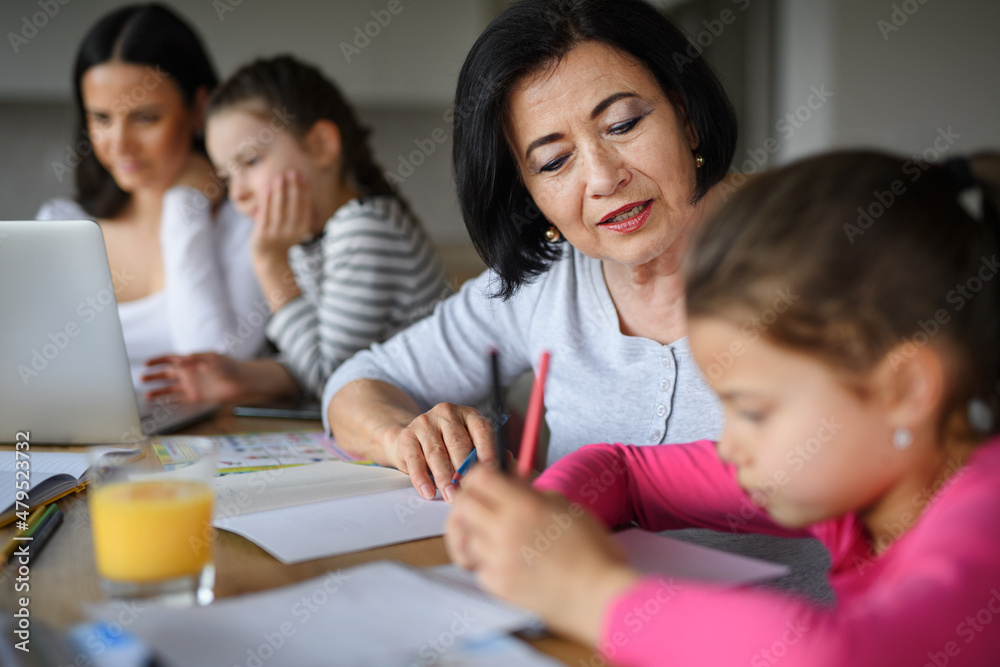 Happy small girls with mother and grandmother doing homework using laptop indoors at home. Happy small girls with mother and grandmother doing homework using laptop indoors at home.