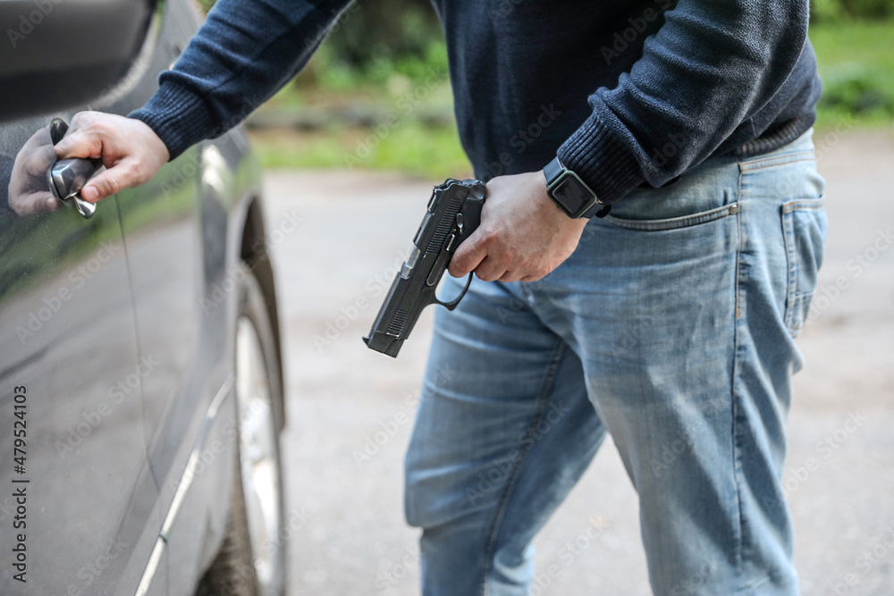 A man with a pistol in the parking lot opens the car. Crime, robbery. A man with a pistol in the parking lot opens the car. Crime, robbery.