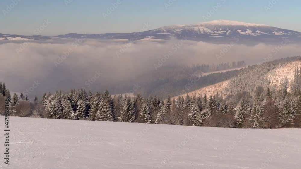 Slow tilt up over magical winter landscape with snowy hill, trees and mountain Slow tilt up over magical winter landscape with snowy hill, trees and mountain