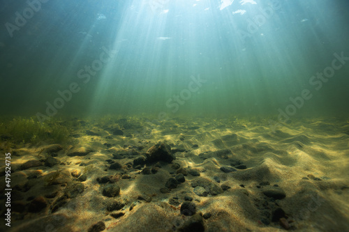 Beautiful sand bottom in sunlight. Sea floor view of small stones on a sand. Crystal clear lake water, underwater photography. photo