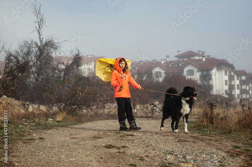 Girl with a dog walking in foggy weather in the forest