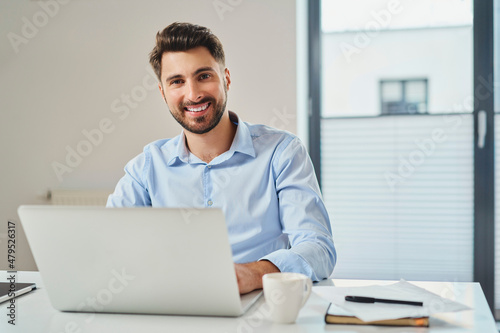 Portrait of young businessman smiling sitting by the desk