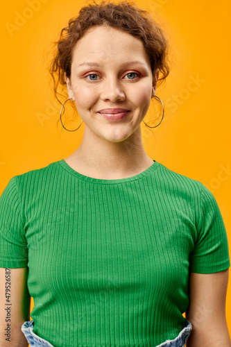 cheerful cute girl with earrings green t-shirts yellow background © Tatiana