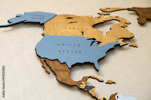 Wooden map of the world on the wall.  Mainland North America continent with the names of countries and capitals. Geographic concept of plywood, laser cutting. photo