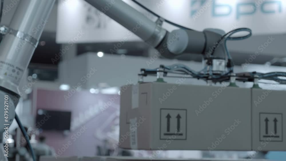 A robot arm uses vacuum suction cups to transport cardboard boxes to the desired location A robot arm uses vacuum suction cups to transport cardboard boxes to the desired location