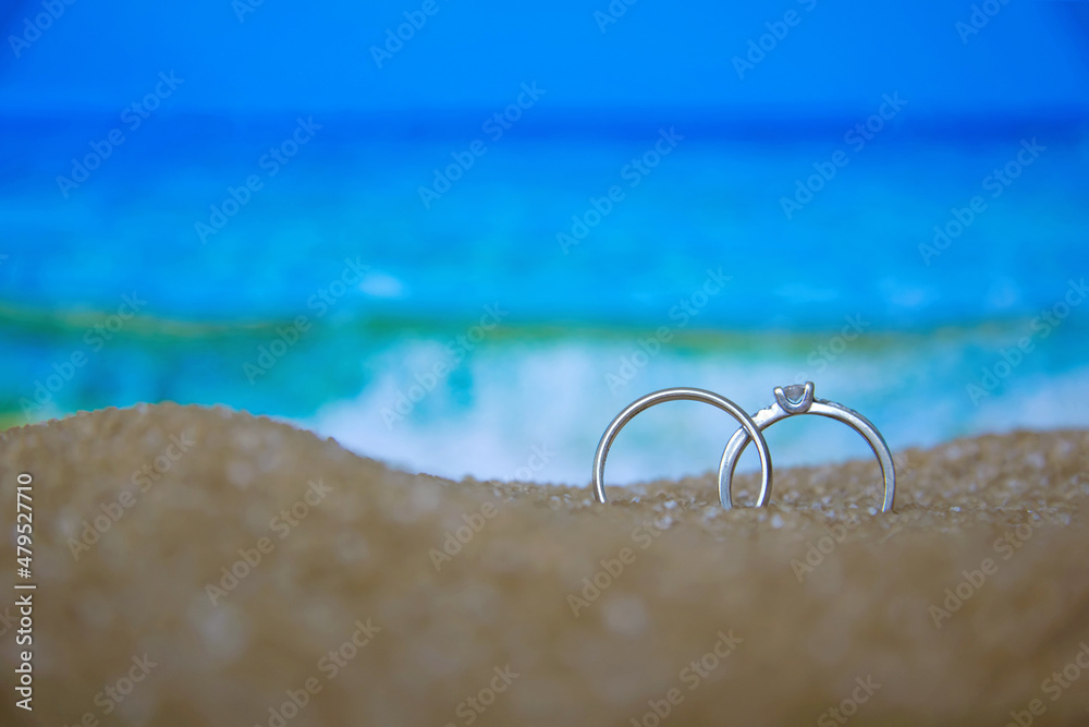 Two wedding silver rings in the sand on the background of beach and sea. Two wedding silver rings in the sand on the background of beach and sea.