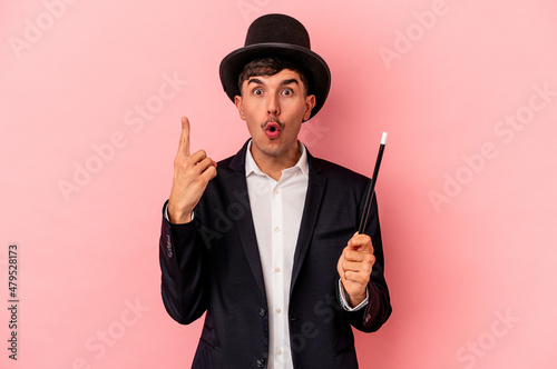 Young caucasian wizard man holding a wand isolated on pink background having some great idea, concept of creativity.