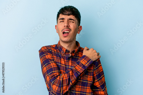 Young mixed race man isolated on blue background having a shoulder pain.