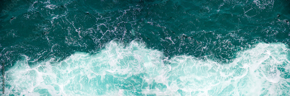 Fototapeta premium Raging sea with foam on the crest of a wave. Blue water background, banner