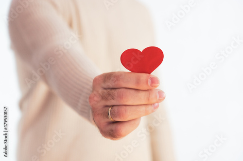 Unrecognizable man holding small red heart in his hand