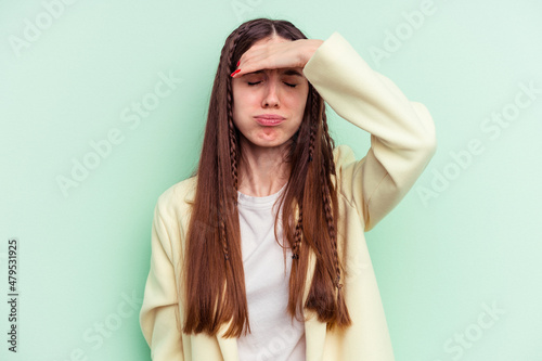 Young caucasian woman isolated on green background touching temples and having headache.
