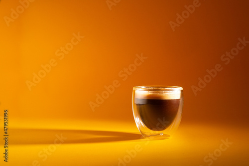 Freshly brewed creamy espresso in a glass coffee cup isolated on yellow backgrou Fotobehang