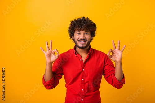 I am ok. Portrait of cheerful brown-haired man with beard and mustache in casual shirt looking at camera and showing okay hand gesture. Indoor studio shot isolated on orange background